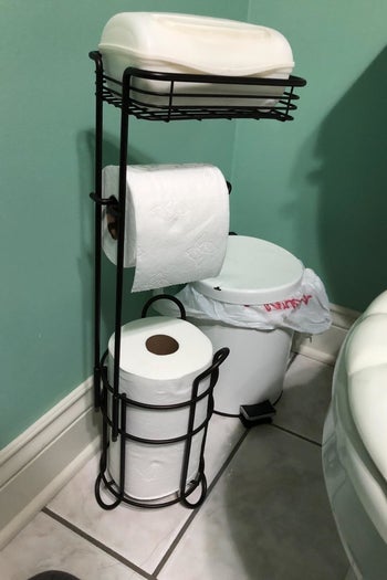 a reviewer photo of a black toilet paper stand with a tray on top holding wet wipes