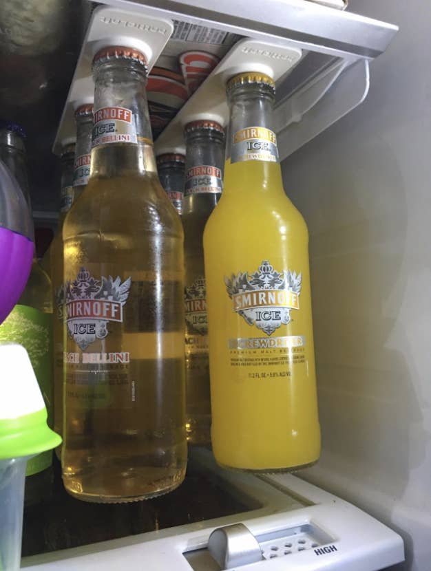 two wine coolers in bottles hanging from a magnet in the fridge