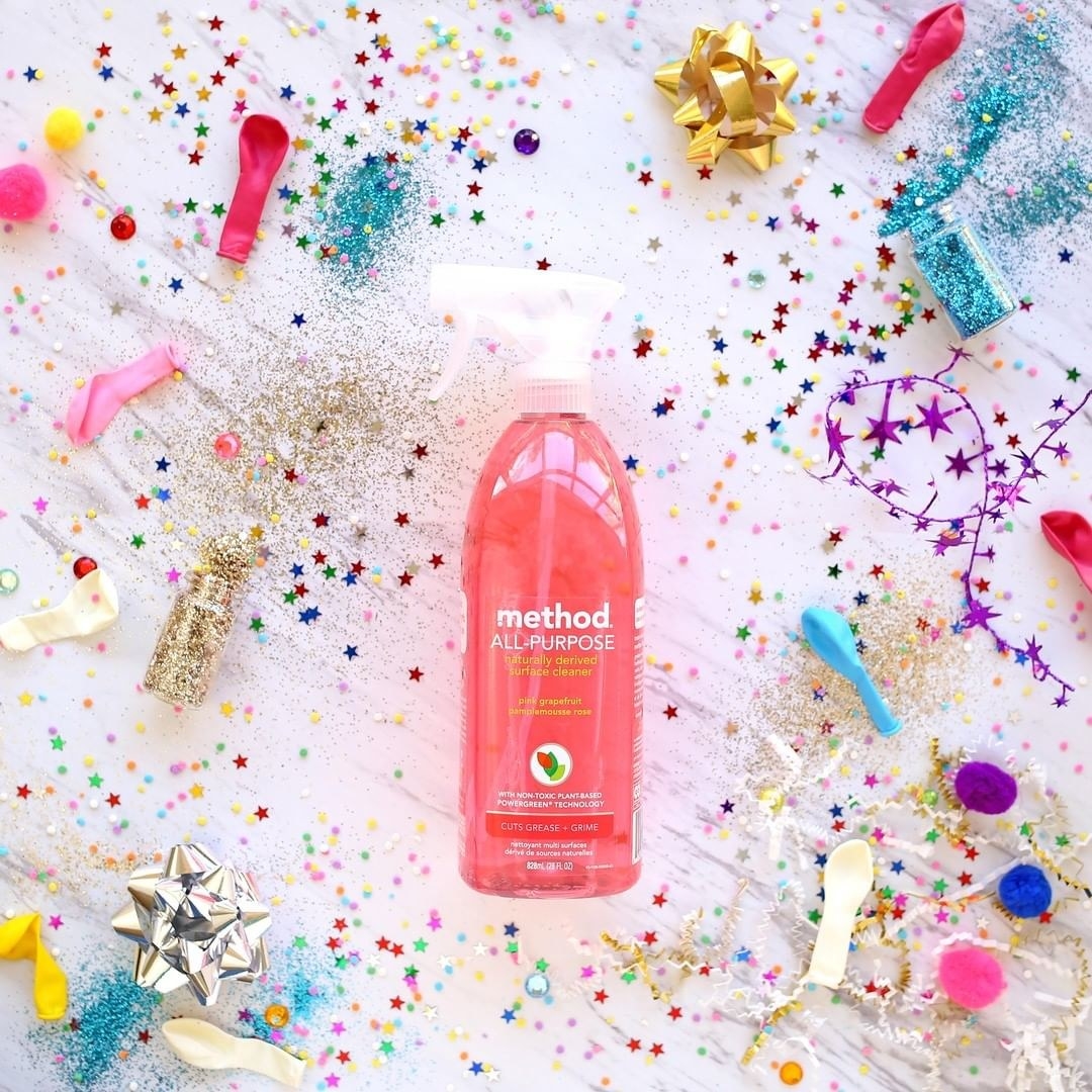 a pink spray bottle of all purpose cleaner on top of confetti and balloons