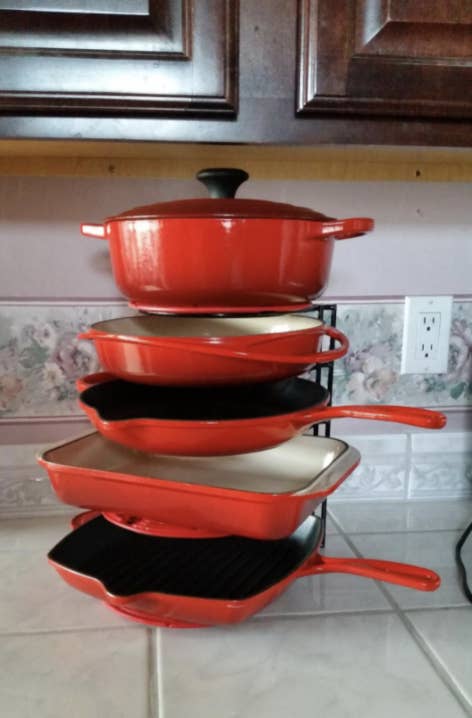 five pieces of red Le Creuset cast iron on this vertical organizer