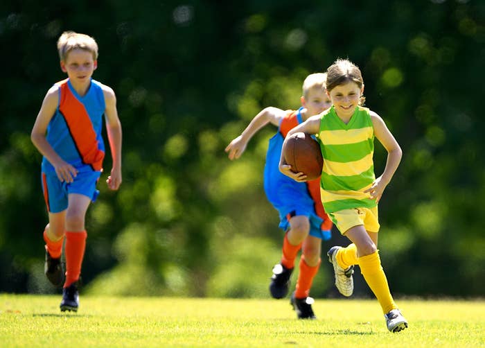 A girl and two boys play rugby