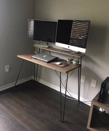 Another reviewer's desk with two large monitors on the top tier and a laptop on the bottom tier