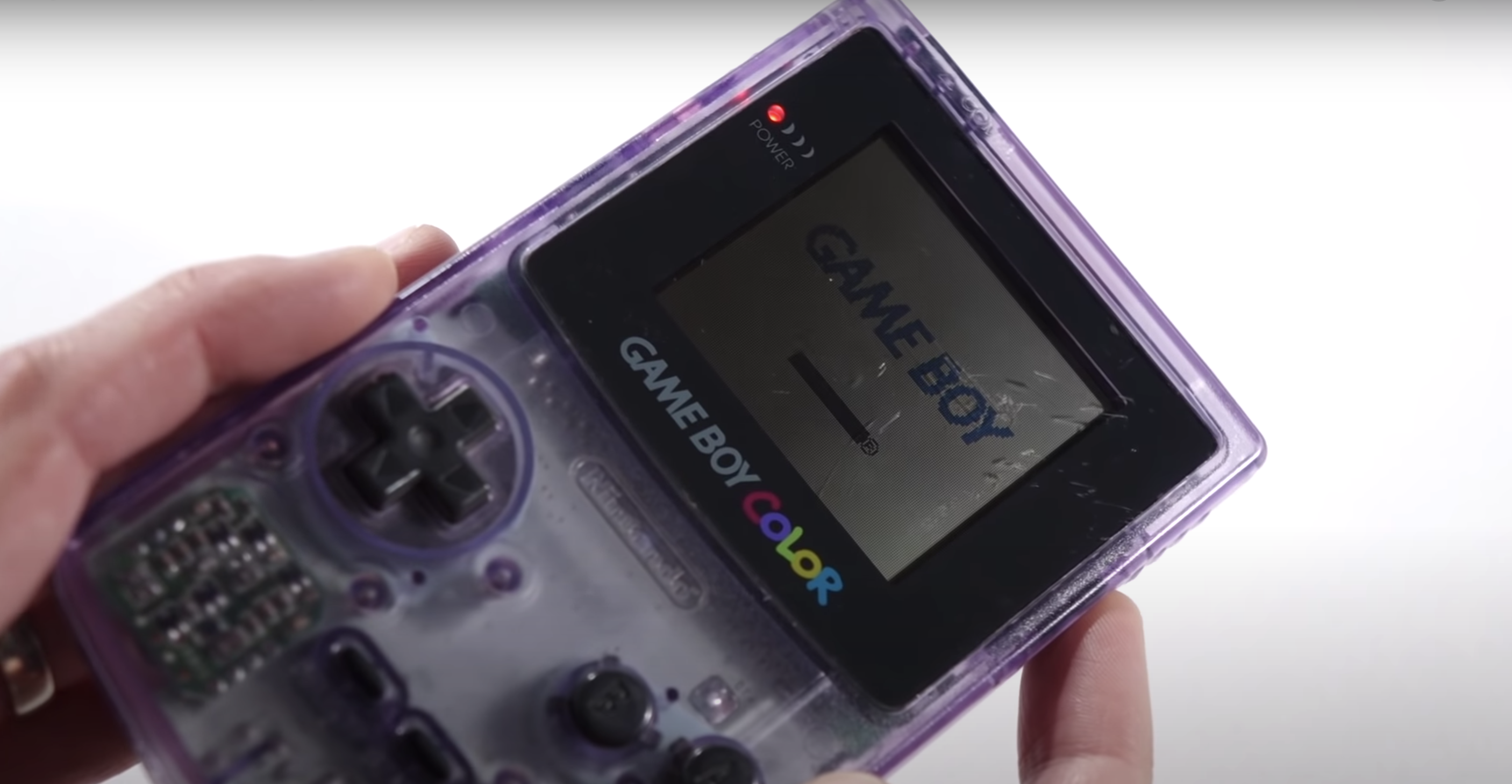 Someone holds up a dim Game Boy Color that does not have backlighting