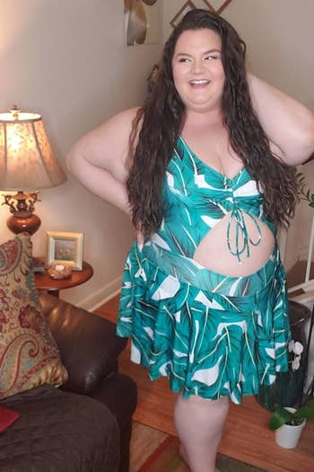 reviewer wearing the palm leaf-print swimdress with a V-neck and cutout at the stomach