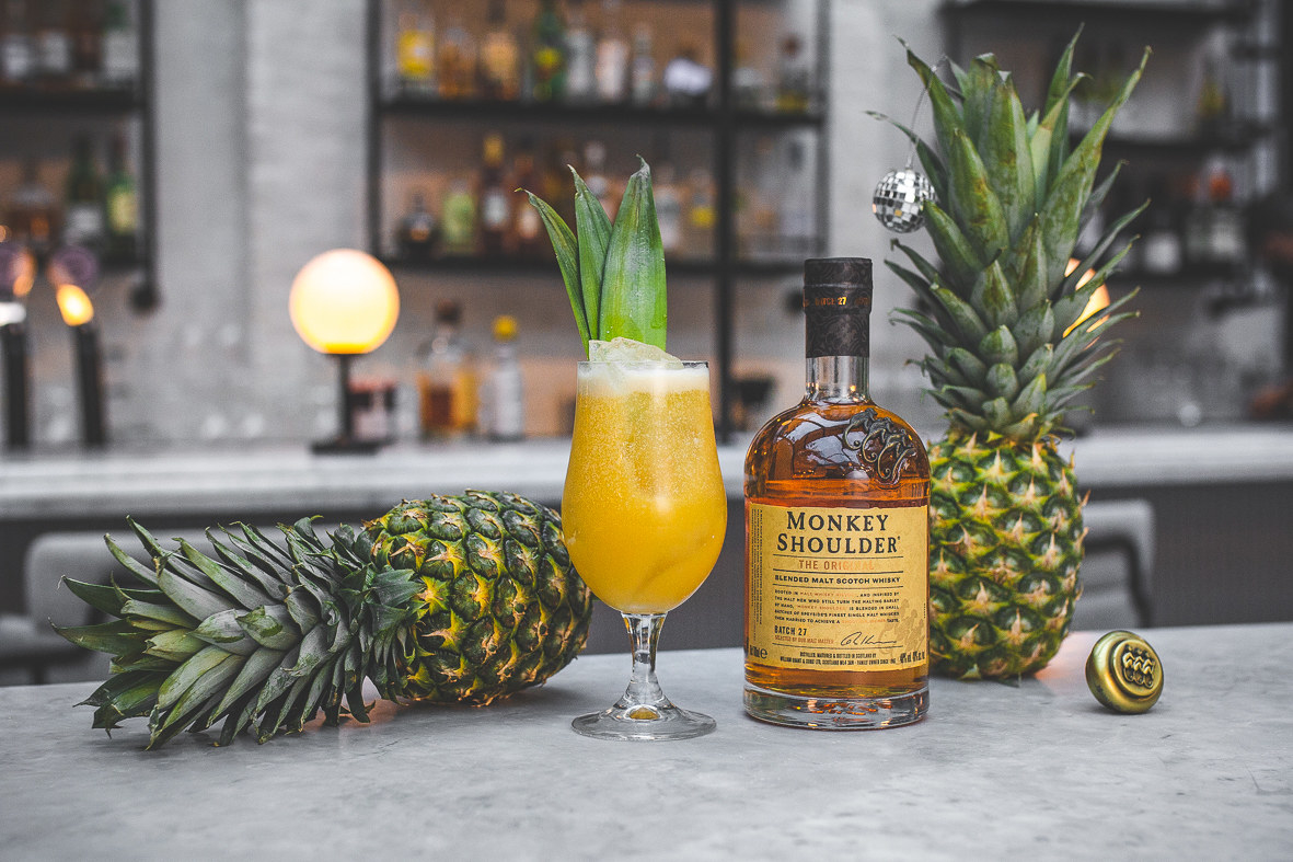 tropical cocktail with pineapples and bottle of monkey shoulder whisky