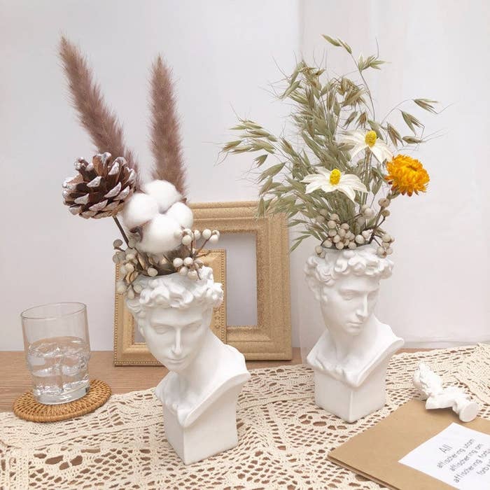 Two bust vases with flowers in them