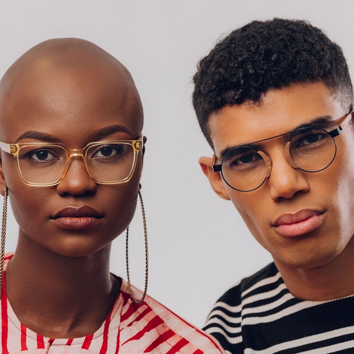 a model wearing square plastic frames and a model wearing black metal frames with wooden nose pieces