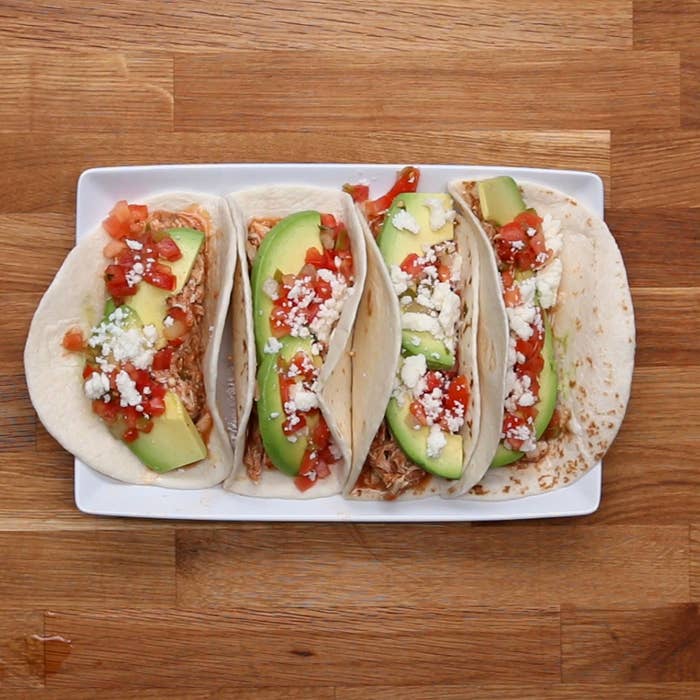 Slow cooker chicken tacos with avocado, queso, and tomatoes.