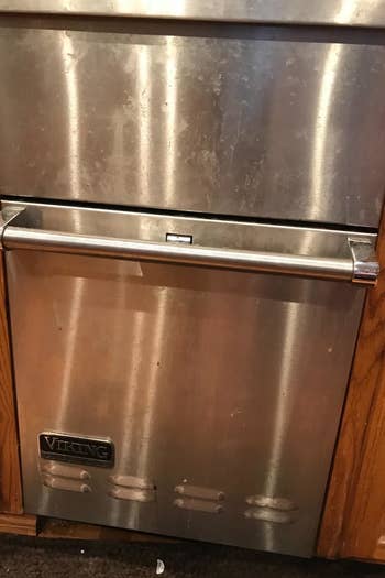 a reviewer photo of a stainless steel dishwasher with marks and smudges all over it 