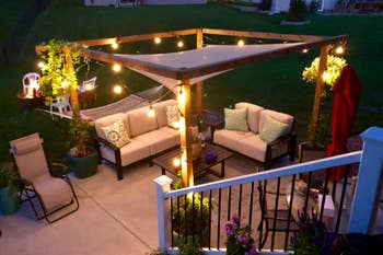 Reviewer's backyard at night, with the canopy above a wooden frame that is covered in twinkle lights 