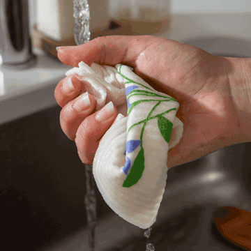 a gif of a hand squeezing a dish cloth over a kitchen sink