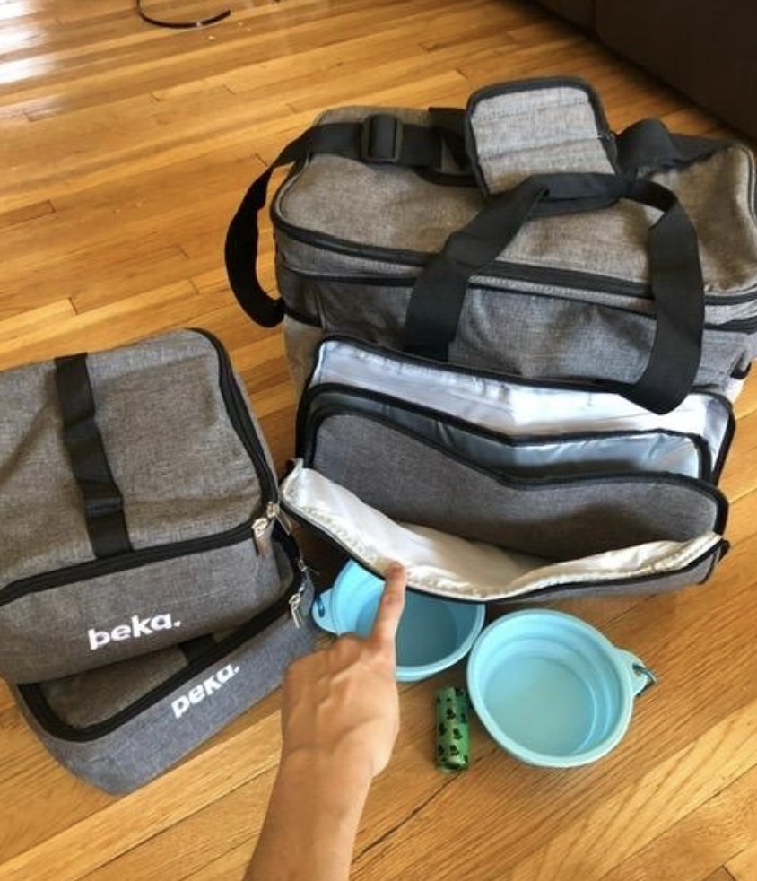 a reviewer opening the front pocket of the grey travel kit