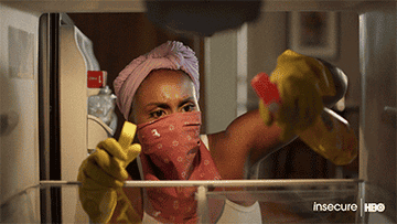 a gif of Issa Rae in &quot;Insecure&quot; wearing a bandanna face mask and cleaning 
