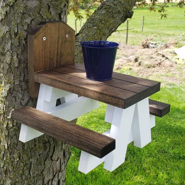 Farmhouse picnic table mounted to a tree trunk with a metal bucket on the table top
