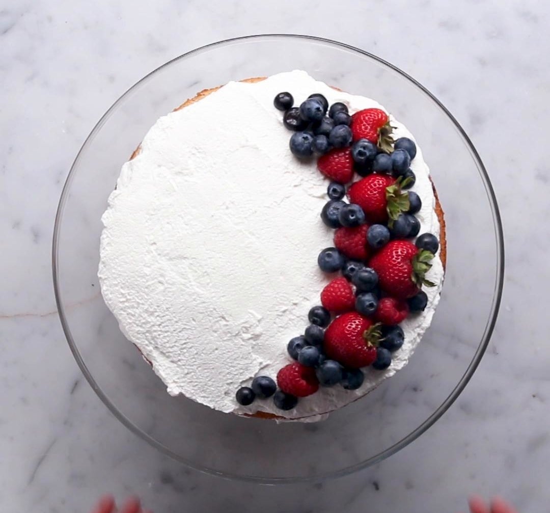 A tres leches cake with strawberries and blueberries.