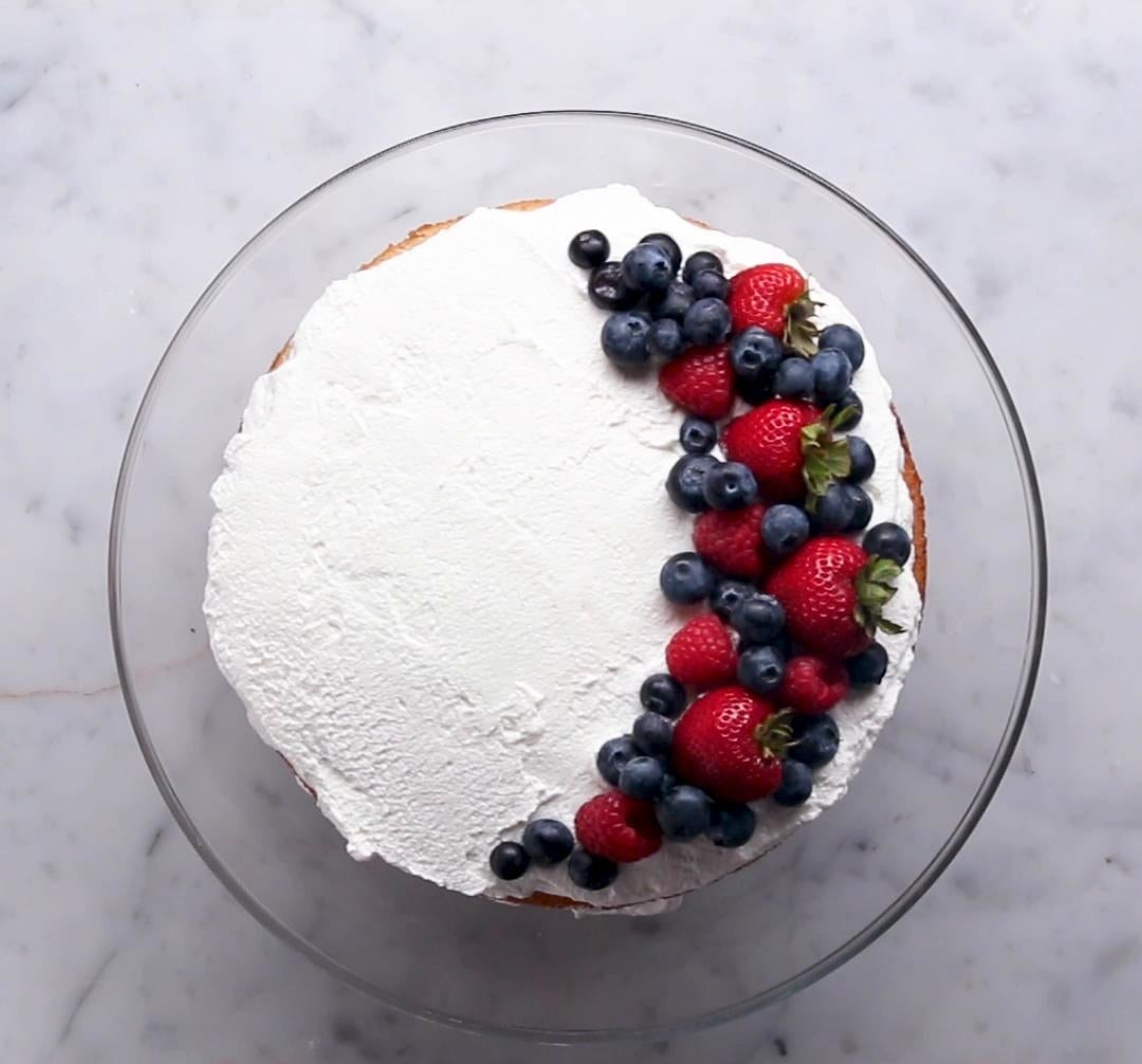 A tres leches cake with strawberries and blueberries.