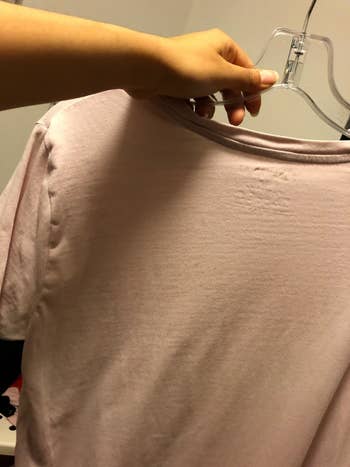 Reviewer holding unwrinkled shirt after using wrinkle release spray