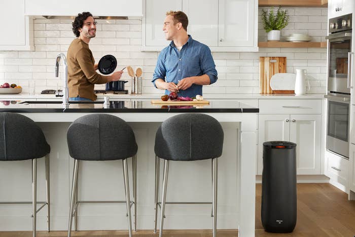 couple in kitchen with black tower air purifier beside a kitchen island