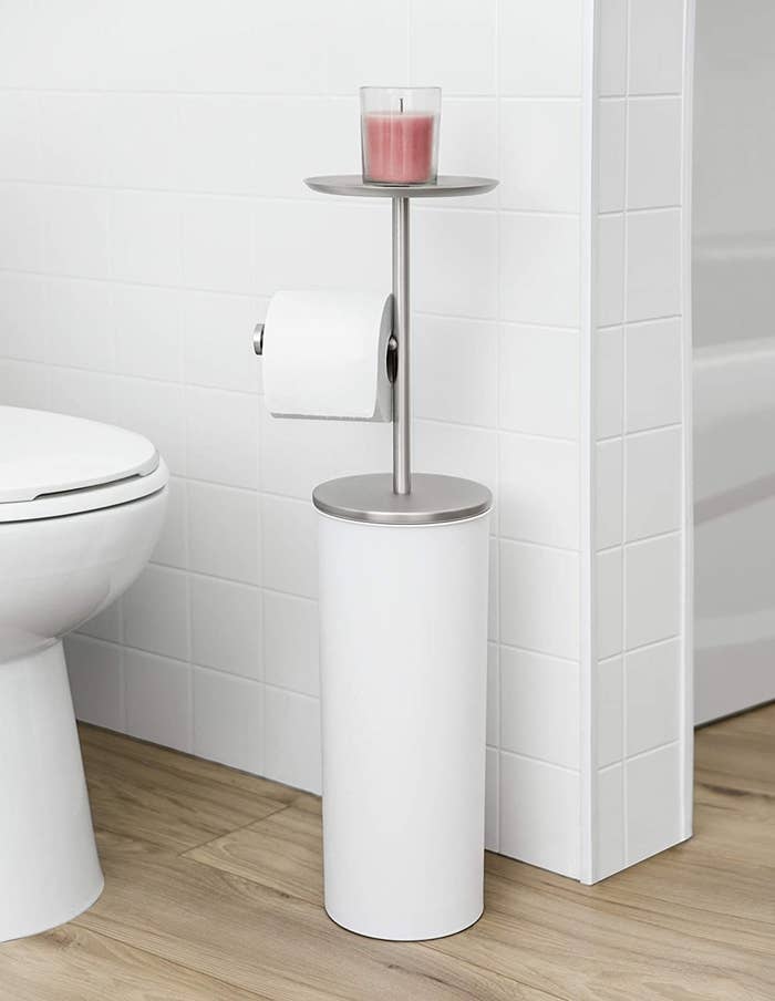 A toilet paper stand with several perches for toilet paper, phones, and candles