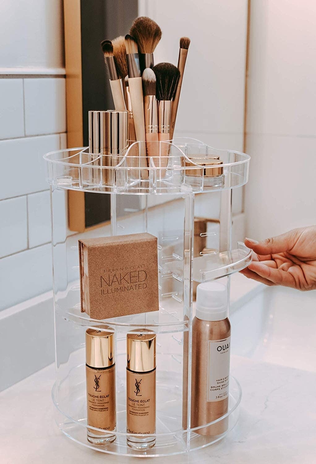 A person pulling out one of the shelving trays on the rotating caddy that is holding various beauty products 