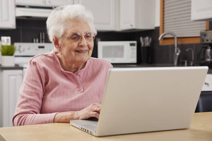 An old woman smiling at her laptop screen