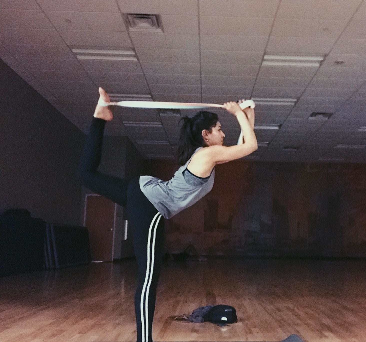 reviewer using the strap to lift their leg behind them