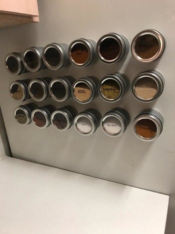 a reviewer photo of three rows of six round spice jars mounted on a wall 