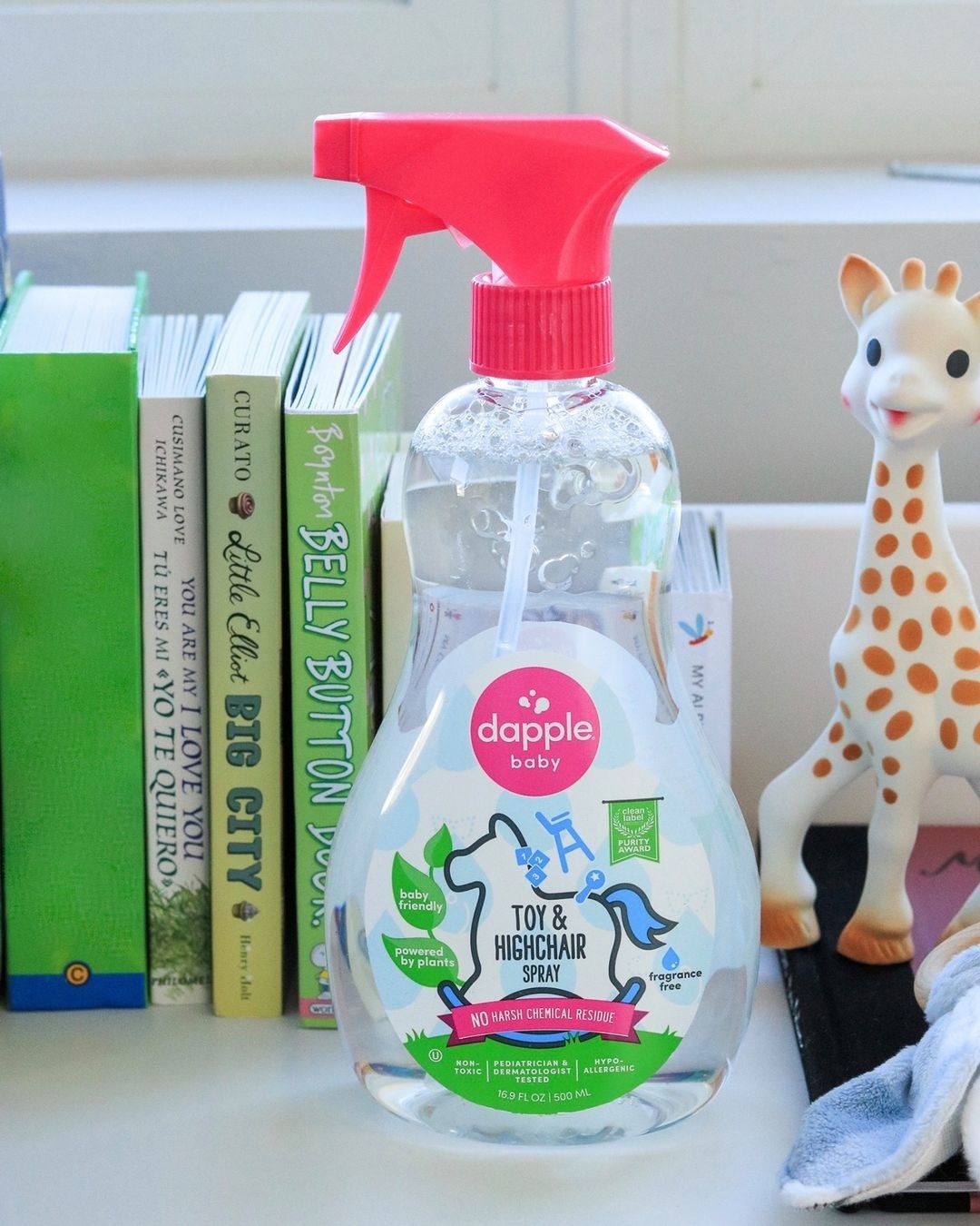 A bottle of toy and highchair spray on a bookshelf next to children&#x27;s toys