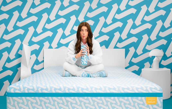 Charlie drinking from a water bottle and sitting on the mattress