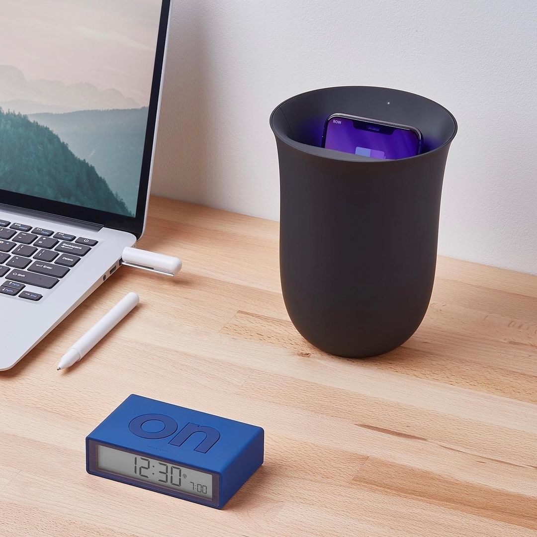A vase-shaped phone sanitizer and charging station on a neat desk
