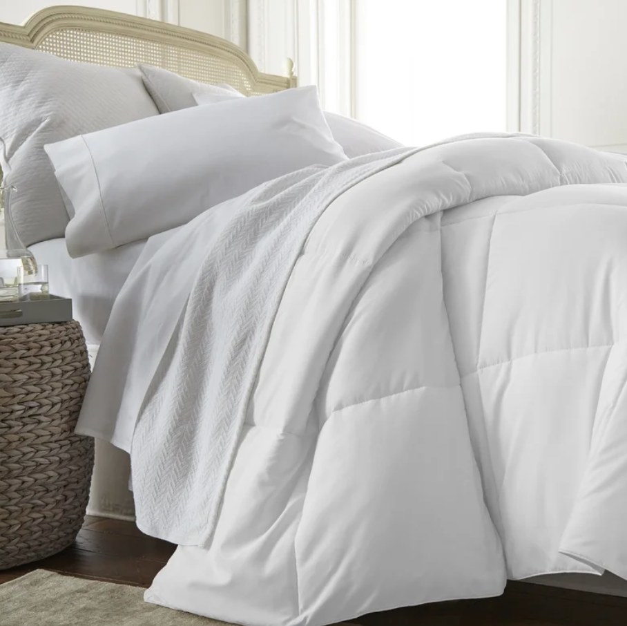 A white, microfiber down comforter draped over a bed