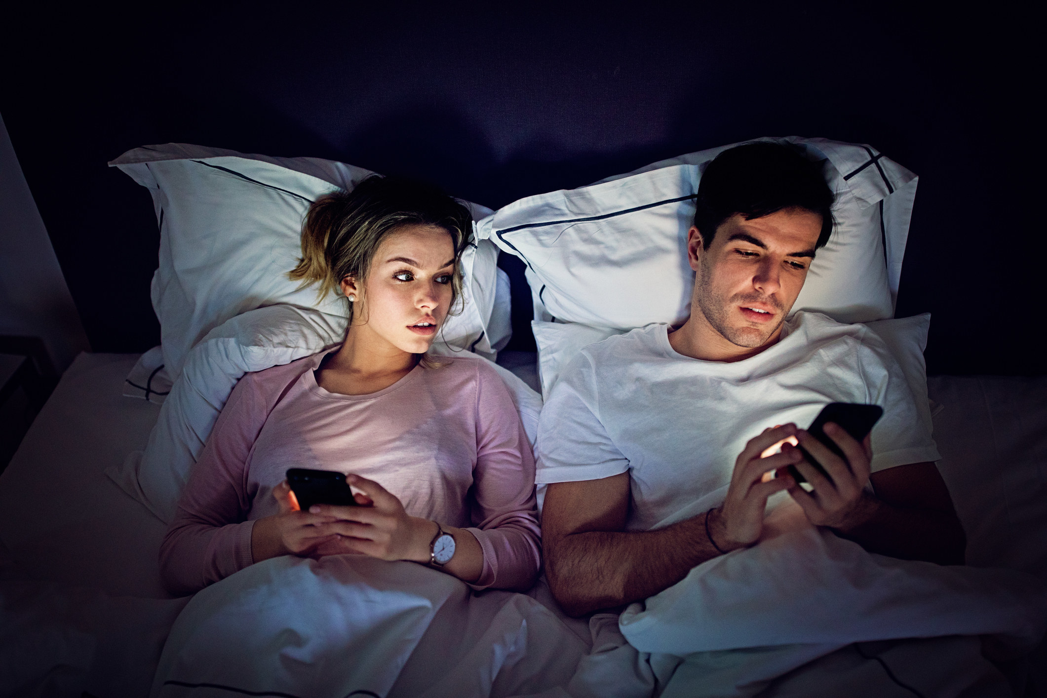 Girlfriend is peeking her boyfriend texting in the bed