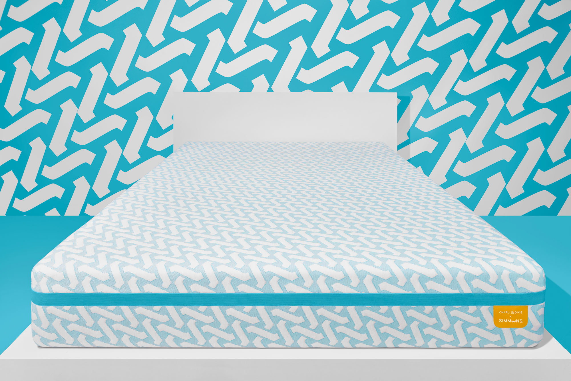 A blue and white Simmons mattress against a blue and white patterned wall.