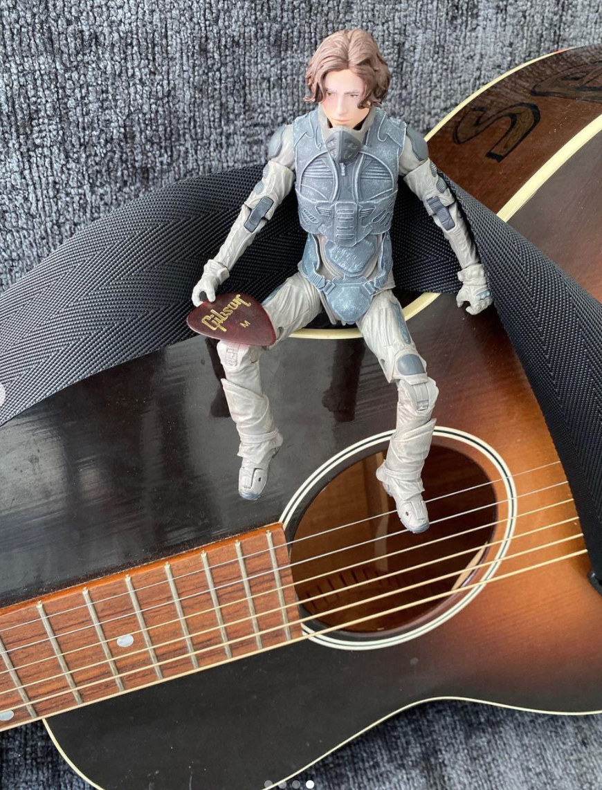 Chalamet&#x27;s action figure sitting on top of a guitar