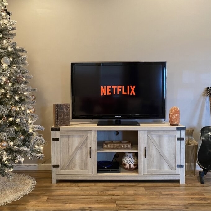 A reviewer image of the TV stand, which has a cabinet door on either end, and two open storage shelves in the middle