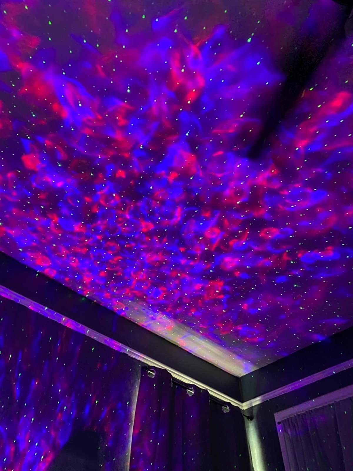 reviewer image of the galaxy projector filling a bedroom with blue and purple light