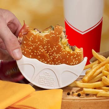 Hand holding a burger in the white half-circle holder