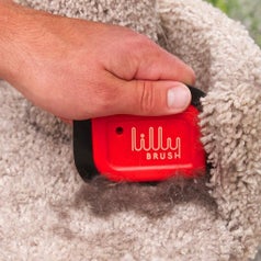 hand using the scraper tool to collect hair from the corner of a cat tree