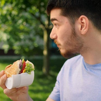 model holding a burger in the holder with one hand