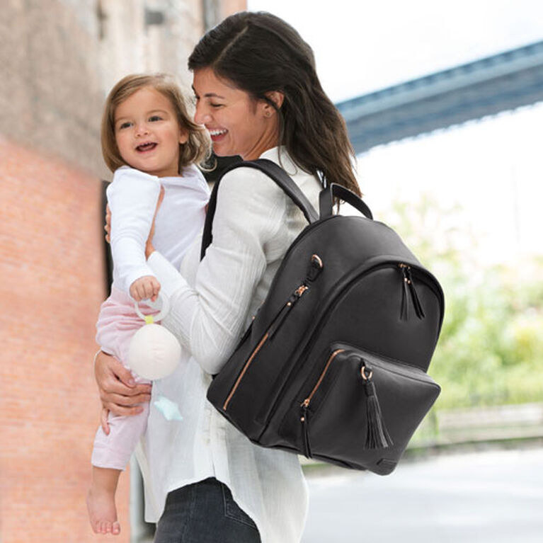 A person carrying a baby and wearing a backpack on one shoulder