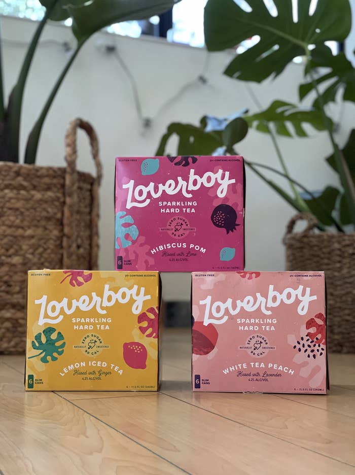 An image of three boxes of Loverboy sparkling hard tea in hibiscus pom, lemon iced tea, and white tea peach flavors