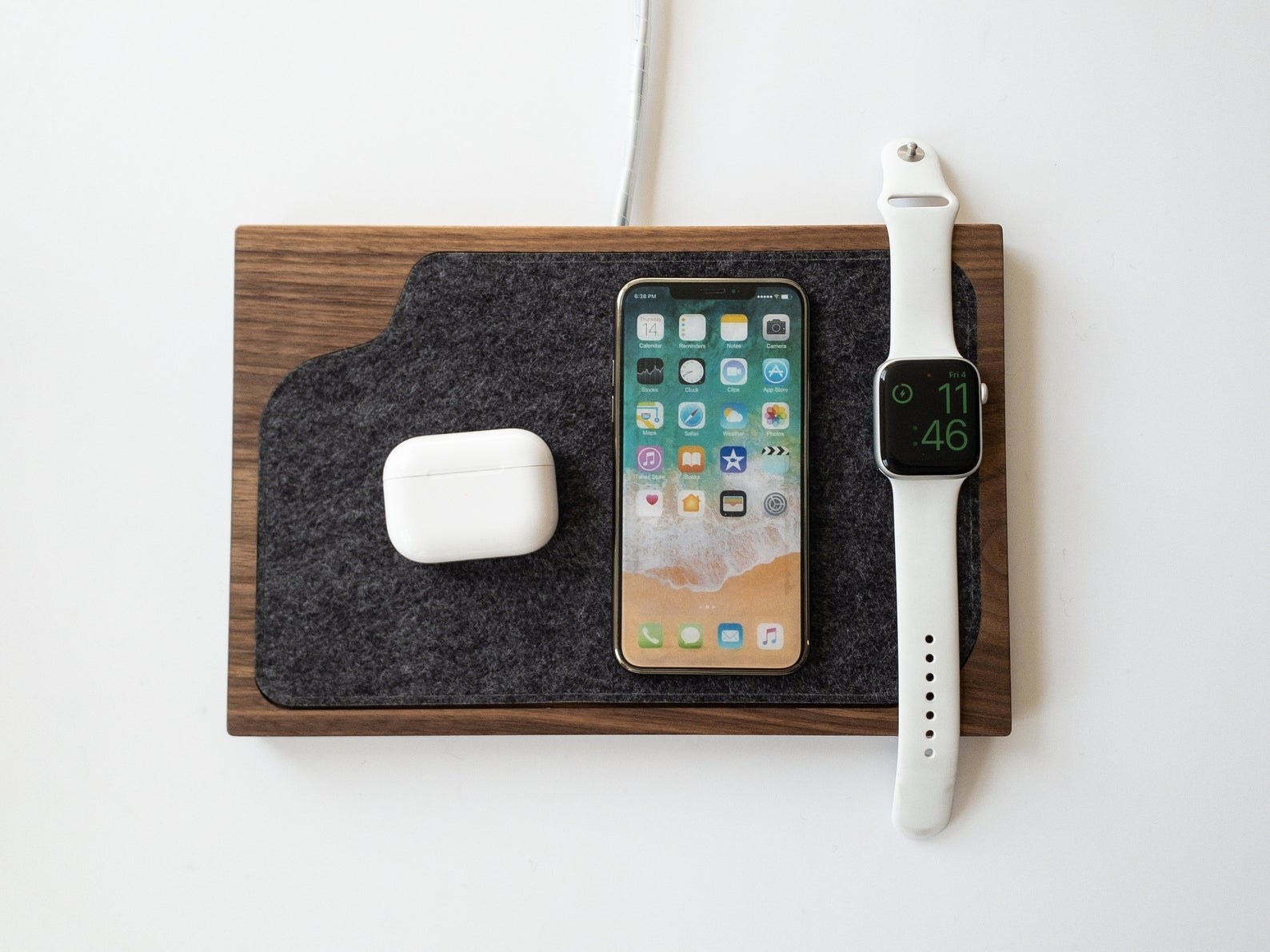 the wireless charging tray with a smart phone, watch, and airpods on it 