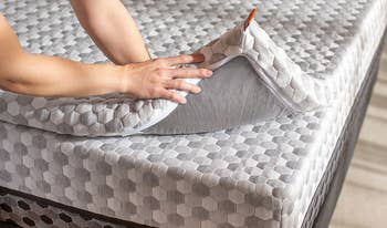 hands placing the topper on a mattress