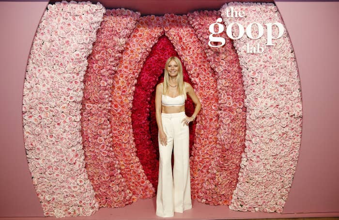 Gwyneth stands in front of a wall of pink flowers