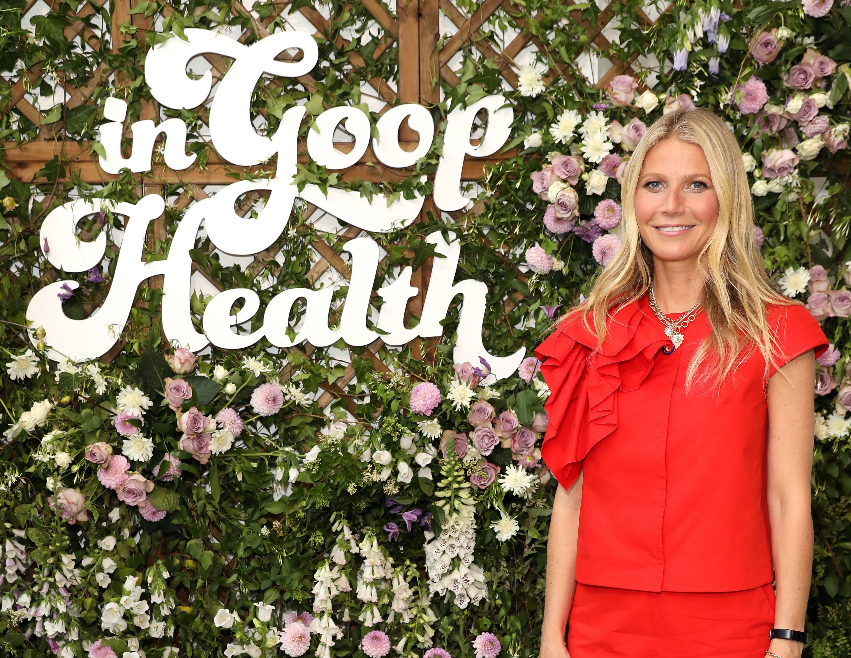 Gwyneth stands in front of a sign that says in goop health