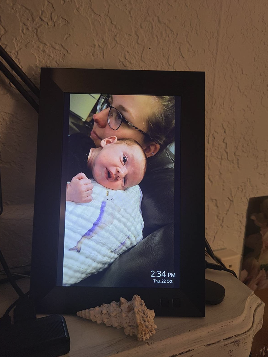 a reviewer&#x27;s picture frame with a photo of a person holding a super cute infant over their shoulder.