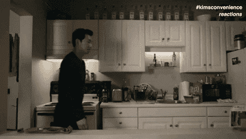 Simu Liu, playing Jung Kim in Kim&#x27;s Convenience, walking into a kitchen, stopping in the middle looking shocked into a camera.