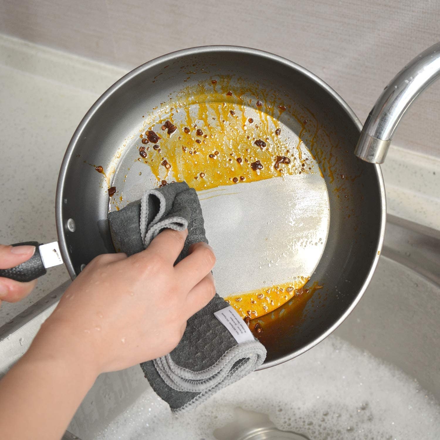 A person wiping down a pan with the cloth