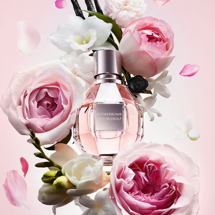 A bottle of perfume surrounded by blooming flowers