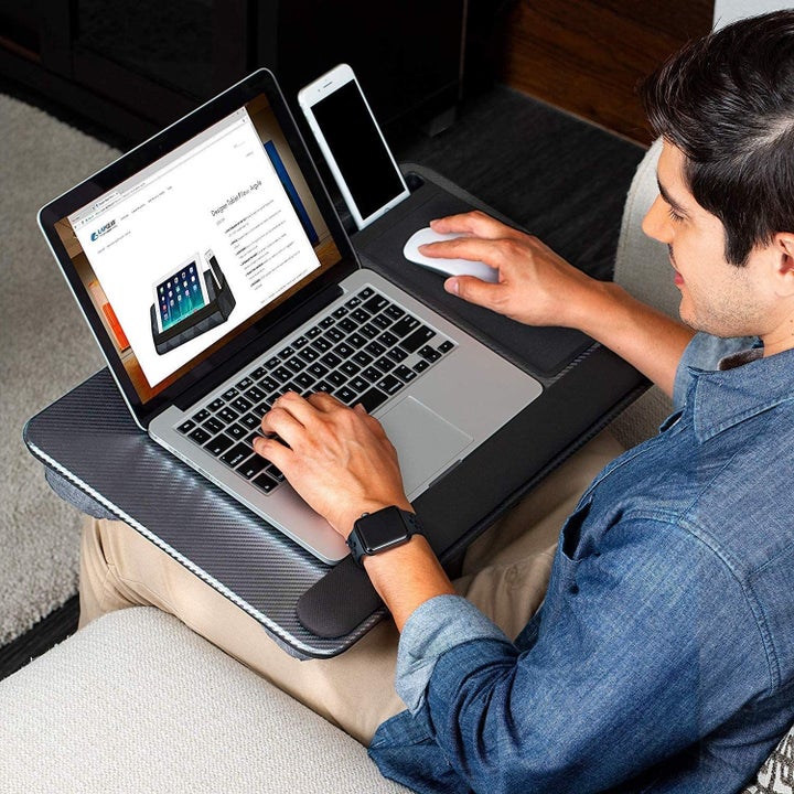 A man sitting with the lap desk and a laptop